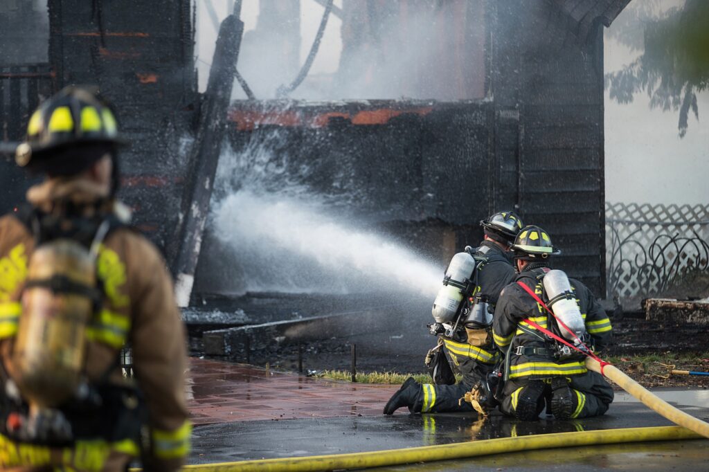 Firefighter sprays water on burning house fire