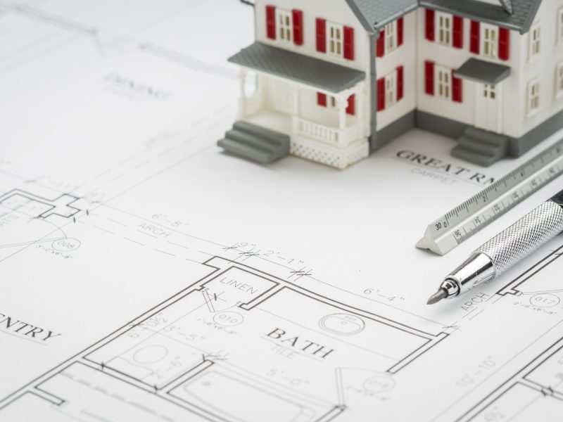 Model Home, Engineer Pencil and Ruler Resting On Custom House Plans.